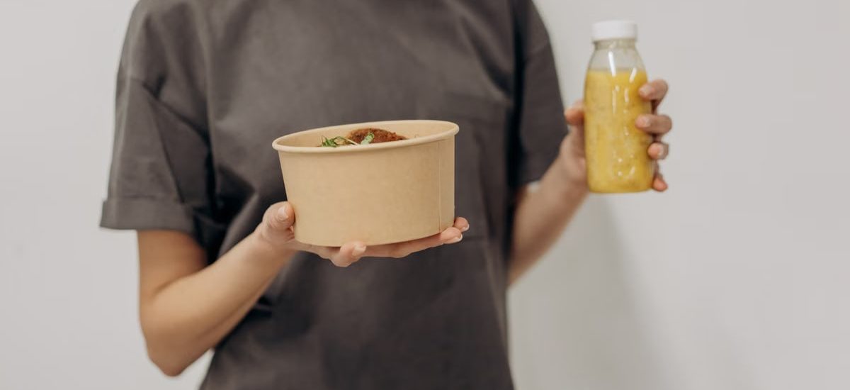 Faceless woman holding a rice bowl and juice bottle, representing healthy lifestyle and nutrition.