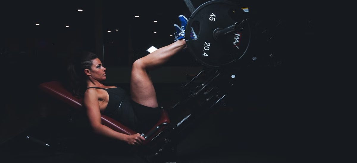 A woman engages in an intense leg press workout at the gym, showcasing strength and fitness.